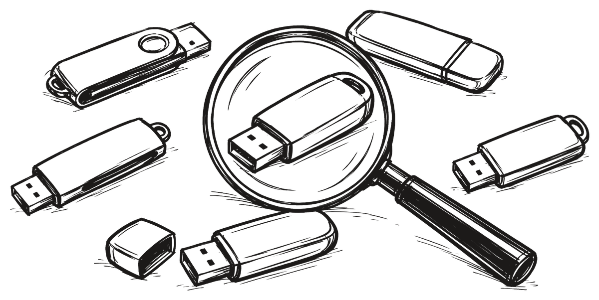 Seis memorias USB esparcidas sobre una mesa, una de ellas con el capuchón quitado, y una lupa encima.